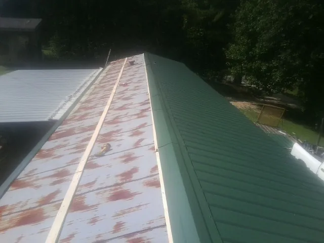 Old rusted panels beside newly installed green metal roofing — Wind Damage Roof Repair by Roofing Brothers in Pauma Valley