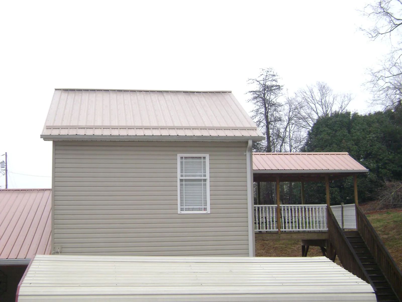 Tan metal roofs on a two story addition and attached porch, from a Roof Replacement job in Pauma Valley