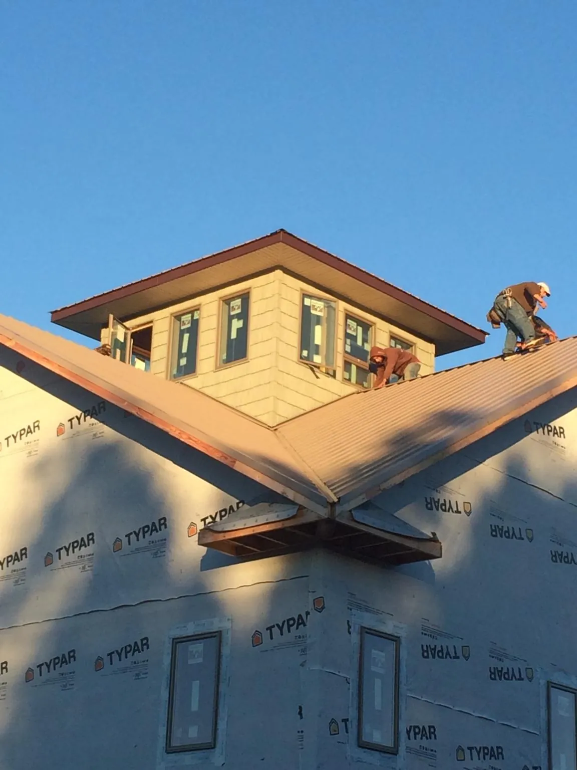 Roofers working around a rooftop cupola on a new metal roof at sunset — Roof Waterproofing in Pauma Valley by Roofing Brothers